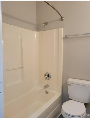 Fort Myers apartment for rent - A white toilet sits next to a white bathtub in a bathroom.