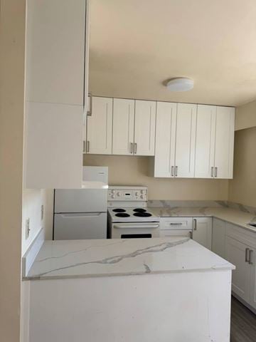 Burnaby apartment for rent - A kitchen with white cabinets and a white stove top oven.