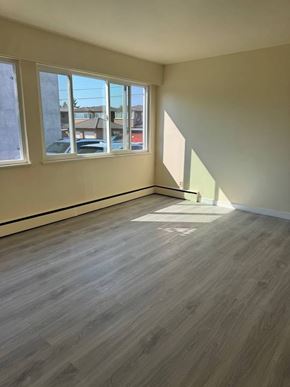 Burnaby apartment for rent - A room with light wood flooring and a window overlooking a street.