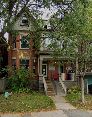 Ottawa apartment for rent - A red brick building with a porch and a tree in front.