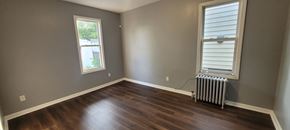 Hillside apartment for rent - A room with a window and a radiator on the floor.