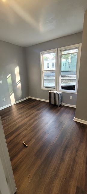 Hillside apartment for rent - A room with wooden floors and a window.