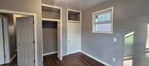 Hillside apartment for rent - A room with a white door, a window with blinds, and a wooden floor.