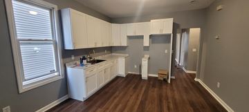 Hillside apartment for rent - A kitchen with white cabinets and a wooden floor.