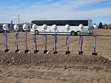 Clint apartment for rent - A row of trees are planted in a field with a bus in the background.