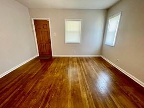 Louisville house for rent - an empty living room with wooden floors and a door