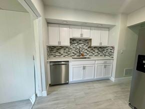 St Petersburg house for rent - a small kitchen with white cabinets and a stainless steel dishwasher