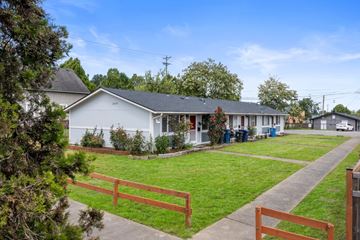 Tacoma apartment for rent - the front yard of a white house with a lawn and a bench