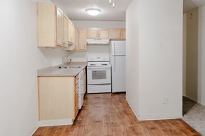 Tigard apartment for rent - A kitchen with white appliances and wooden cabinets.