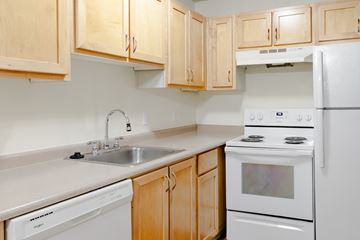 Tigard apartment for rent - A kitchen with wooden cabinets and white appliances.