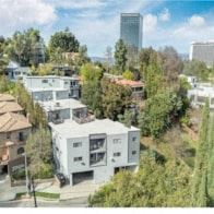 Los Angeles apartment for rent - A modern white house is surrounded by trees and other houses.