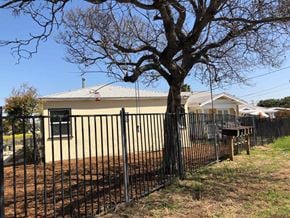 San Diego apartment for rent - A house with a black fence and a tree in front.