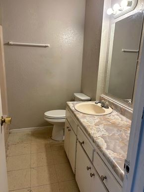 Rosebud apartment for rent - A bathroom with a toilet, sink, and mirror.