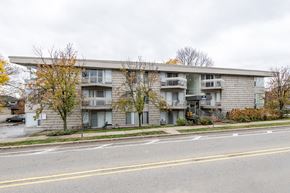Ann Arbor apartment for rent - A grey apartment building with a car parked in front.