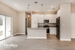 Palm Bay house for rent - an empty kitchen with white cabinets and a black refrigerator