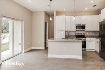 Palm Bay house for rent - a large kitchen with white cabinets and a sliding glass door