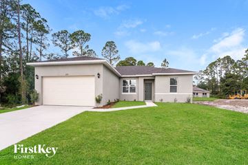 Palm Bay house for rent - a beige house with a lawn and a garage