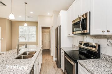 Palm Bay house for rent - a kitchen with granite counter tops and white cabinets and a sink