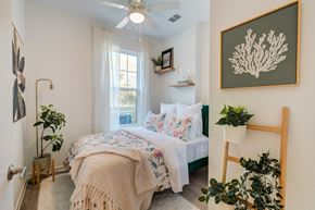 Lakeland apartment for rent - A bedroom with a bed, a plant, and a picture on the wall.