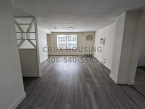 Great Falls apartment for rent - A spacious room with wood flooring and a white wall with a window.