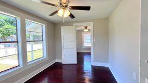 Bay City house for rent - an empty living room with a ceiling fan and large windows