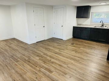 Belding house for rent - a kitchen with a wooden floor and black cabinets