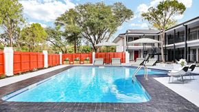 San Antonio apartment for rent - A swimming pool surrounded by a red fence and trees.