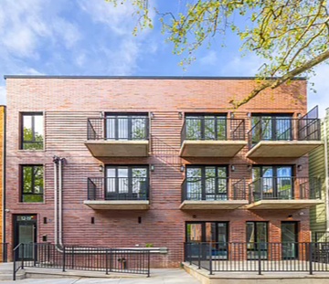 Queens apartment for rent - a brick apartment building with balconies and a blue sky