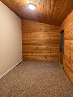 Whitefish apartment for rent - the upstairs bedroom has a wood paneled wall and carpeted floor