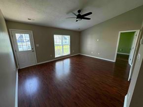Charlotte house for rent - an empty living room with wood floors and a ceiling fan