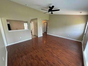 Charlotte house for rent - an empty living room with wood floors and a ceiling fan