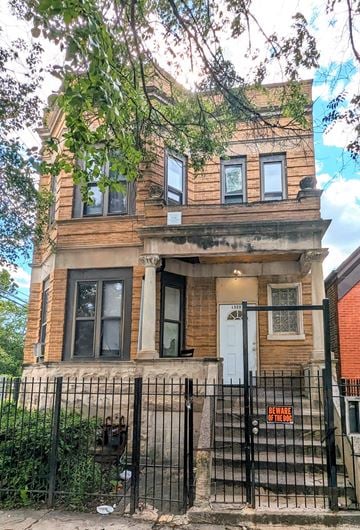 Chicago apartment for rent - A brown house with a black gate and a sign on the stairs.