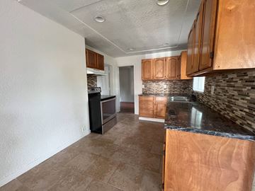 Kelso house for rent - a kitchen with wood cabinets and a black counter top