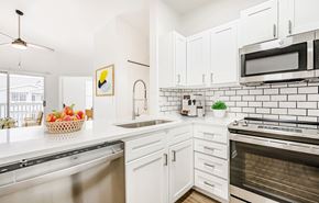 Loveland apartment for rent - A kitchen with white cabinets and a black and white tiled backsplash.