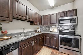 Westminster apartment for rent - A kitchen with dark wood cabinets and stainless steel appliances.