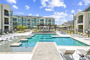 Garland apartment for rent - A large swimming pool surrounded by lounge chairs and apartment buildings.