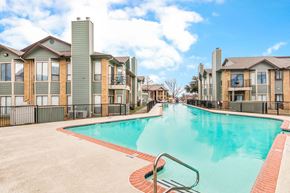 Garland apartment for rent - A swimming pool in front of a row of houses.