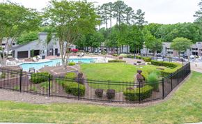 Raleigh apartment for rent - A black fence surrounds a green lawn and a pool.