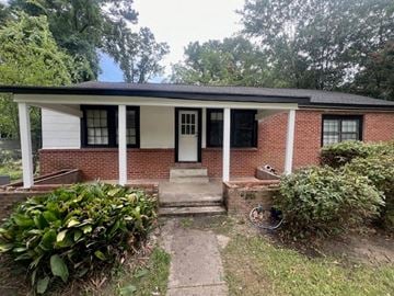Hattiesburg house for rent - a small brick house with white pillars and a porch