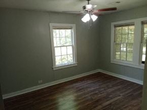 Hattiesburg house for rent - a empty room with a ceiling fan and two windows