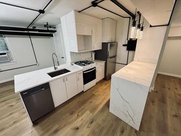 Washington apartment for rent - A kitchen with white cabinets and a black fridge.