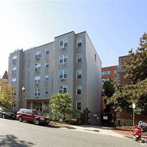 Washington apartment for rent - A red car is parked on the street in front of a tall building.