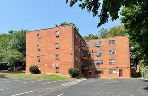 Washington apartment for rent - A red brick building with a parking lot in front.
