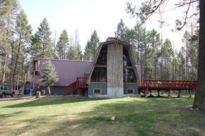 Whitefish apartment for rent - A large building with a red roof and a balcony is surrounded by trees.