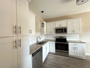 Fayetteville house for rent - A kitchen with white cabinets and a granite countertop.