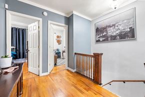 Jersey City apartment for rent - a living room with blue walls and a landing with a wooden railing and a door