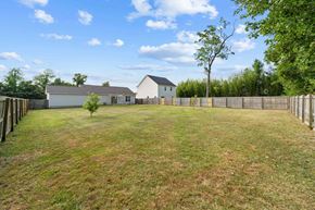 Jacksonville house for rent - A large grassy field with a house and fence in the background.