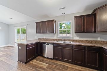 Jacksonville house for rent - A kitchen with dark wood cabinets and a granite countertop.