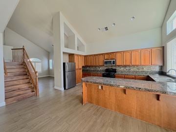 Merced house for rent - a kitchen with granite counter tops and wooden cabinets