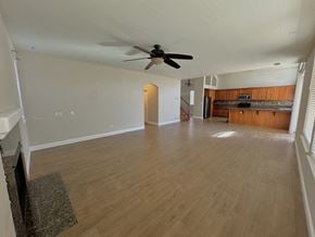 Merced house for rent - an empty living room with a ceiling fan and a kitchen
